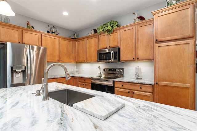 kitchen with light stone counters, sink, decorative backsplash, and stainless steel appliances