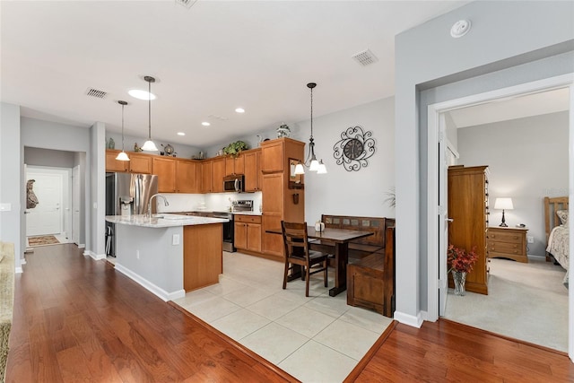 kitchen with light hardwood / wood-style flooring, decorative light fixtures, and appliances with stainless steel finishes