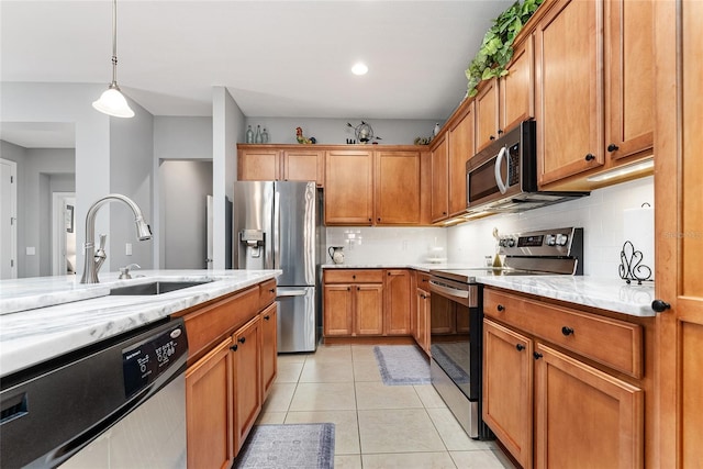 kitchen with sink, hanging light fixtures, decorative backsplash, light tile patterned floors, and appliances with stainless steel finishes