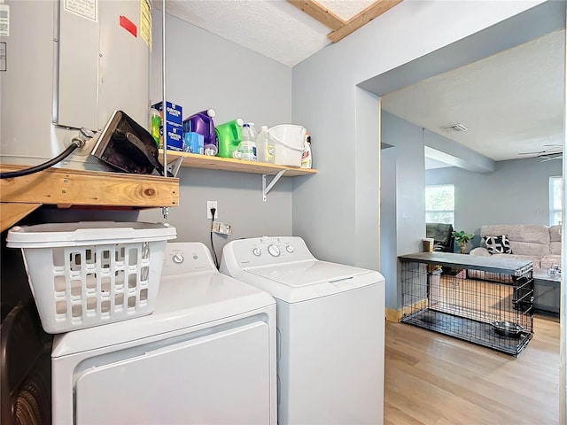 clothes washing area featuring a textured ceiling, light hardwood / wood-style flooring, ceiling fan, and washing machine and clothes dryer