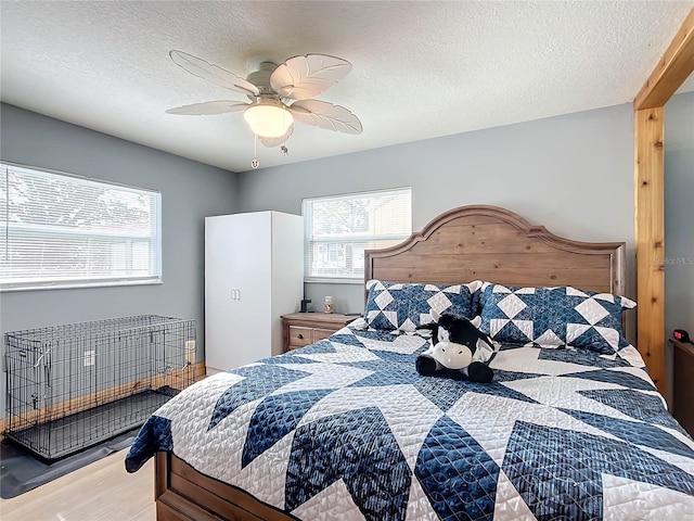 bedroom with ceiling fan, hardwood / wood-style floors, and a textured ceiling