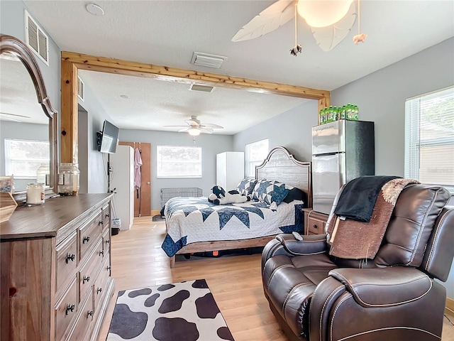 bedroom featuring beamed ceiling, ceiling fan, stainless steel fridge, and light hardwood / wood-style flooring