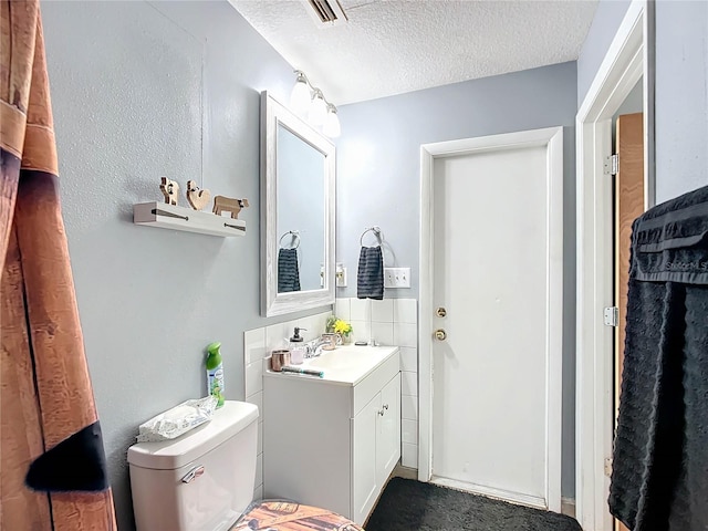 bathroom featuring vanity, a textured ceiling, and toilet