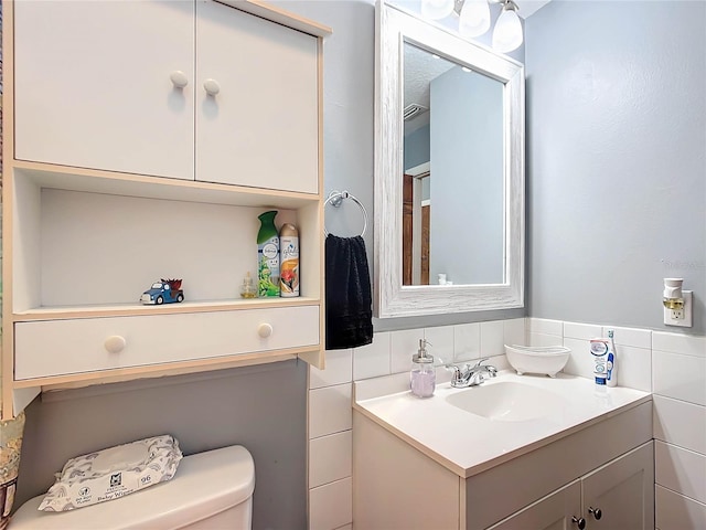 bathroom featuring vanity, tile walls, and toilet