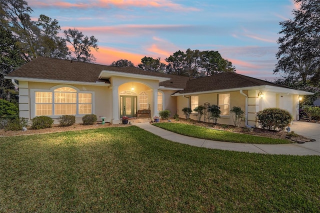 ranch-style house featuring concrete driveway, a front yard, and stucco siding