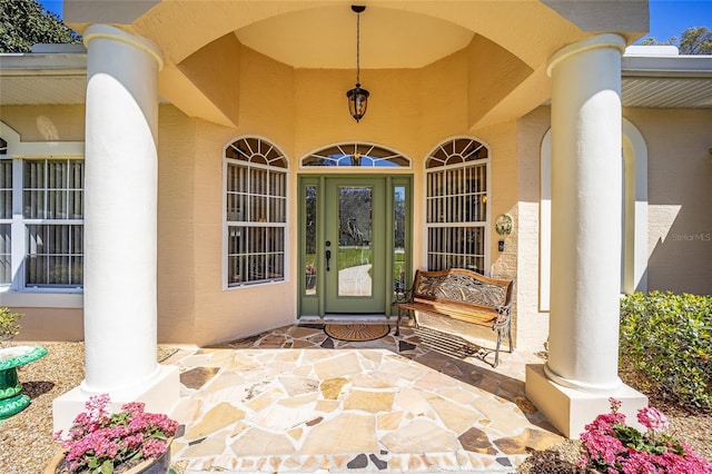 doorway to property with a porch and stucco siding