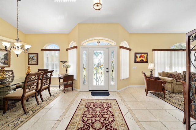 foyer entrance featuring light tile patterned floors, baseboards, and a notable chandelier