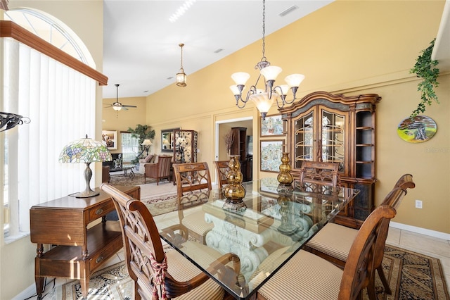 tiled dining room with ceiling fan with notable chandelier, high vaulted ceiling, visible vents, and baseboards