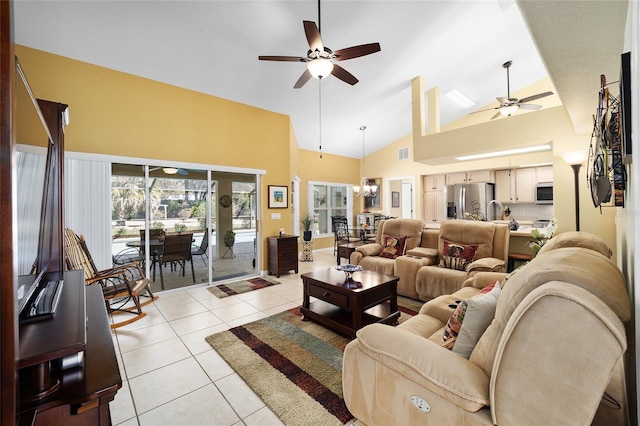 living area featuring high vaulted ceiling, light tile patterned flooring, visible vents, and ceiling fan with notable chandelier