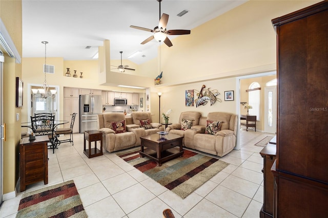 living room with high vaulted ceiling, ceiling fan with notable chandelier, visible vents, and light tile patterned floors