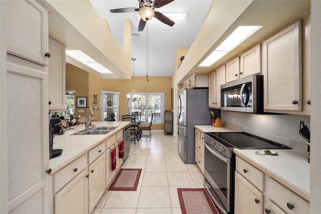 kitchen with appliances with stainless steel finishes, light countertops, a sink, and light tile patterned floors