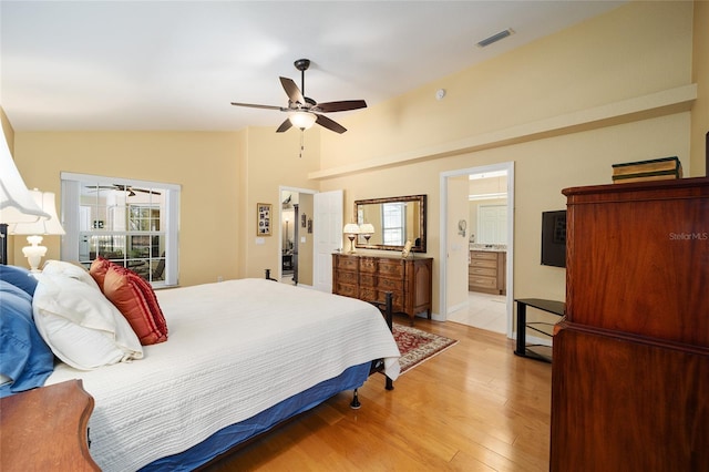 bedroom with ceiling fan, connected bathroom, visible vents, light wood-style floors, and vaulted ceiling