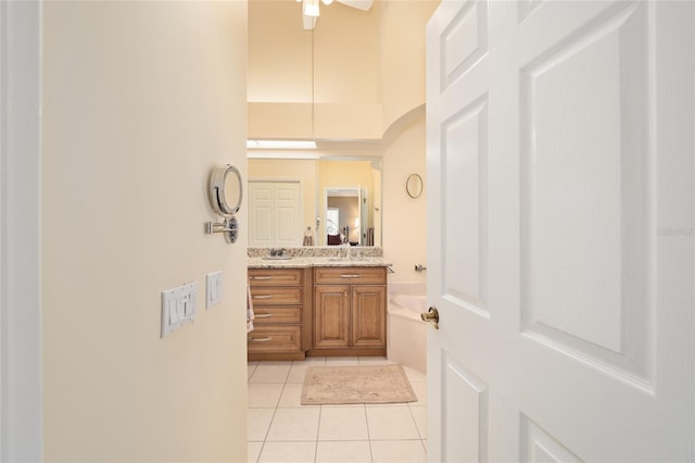 bathroom featuring double vanity, tile patterned flooring, a high ceiling, and a sink