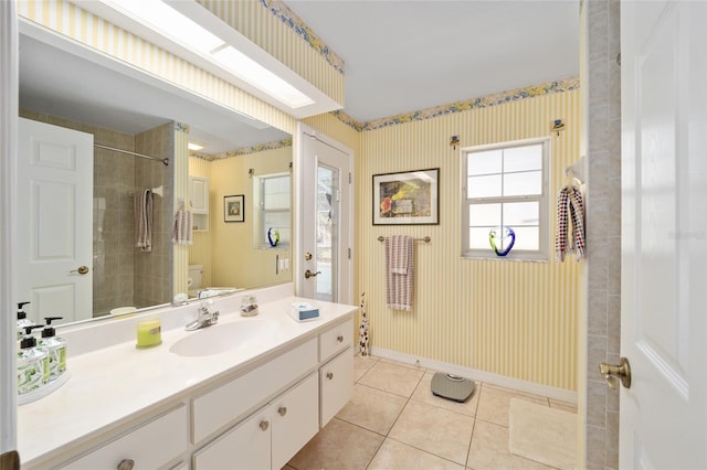 full bath with toilet, a tile shower, vanity, baseboards, and tile patterned floors