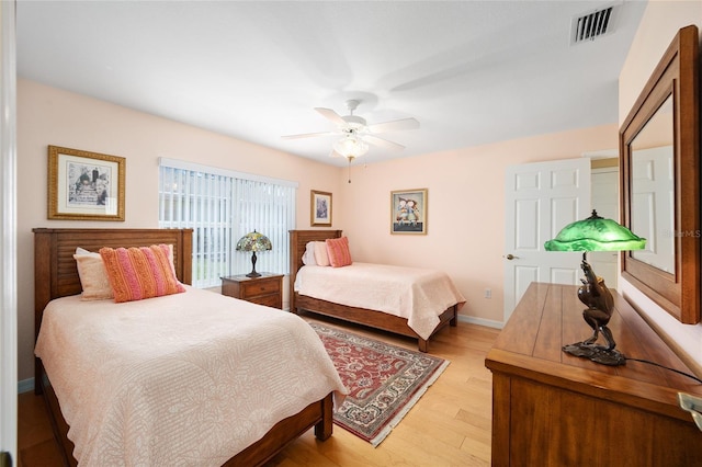 bedroom with ceiling fan, light wood-type flooring, visible vents, and baseboards