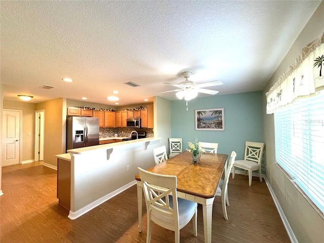 dining area featuring a textured ceiling, dark hardwood / wood-style flooring, ceiling fan, and sink