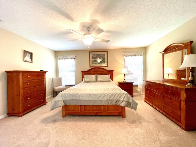 bedroom featuring a textured ceiling, ceiling fan, and light carpet