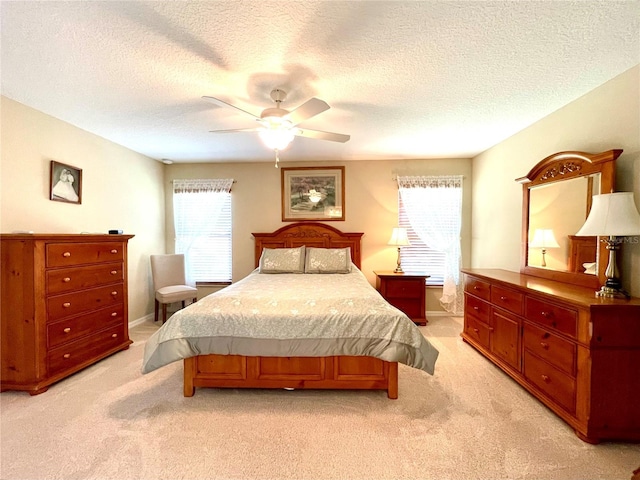 bedroom with multiple windows, ceiling fan, light colored carpet, and a textured ceiling