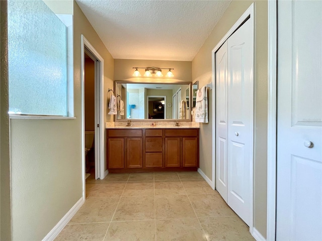 bathroom featuring tile patterned flooring, vanity, toilet, and a textured ceiling