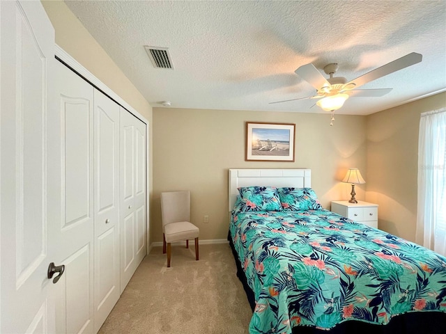 carpeted bedroom featuring a textured ceiling, a closet, and ceiling fan