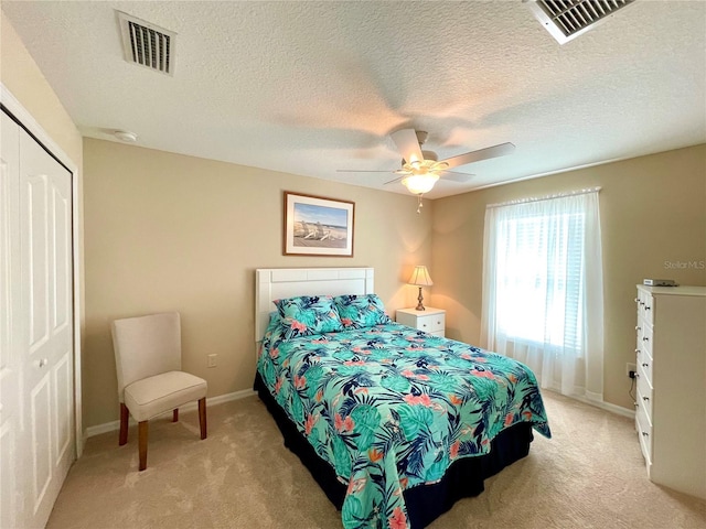 carpeted bedroom with ceiling fan, a textured ceiling, and a closet