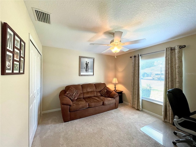 carpeted office featuring ceiling fan and a textured ceiling