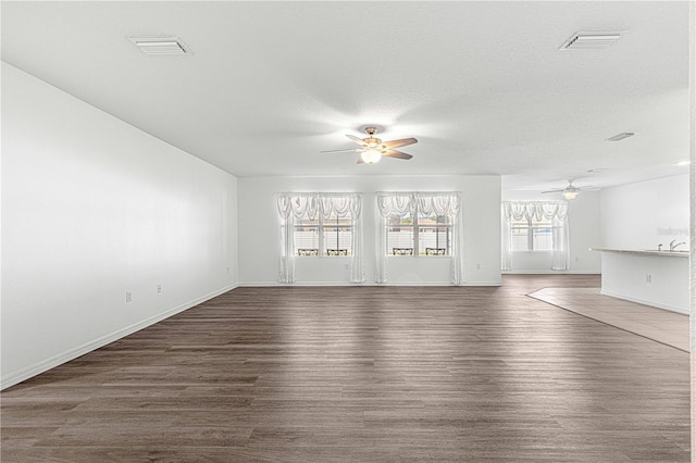 unfurnished living room with ceiling fan, dark wood-type flooring, and a textured ceiling