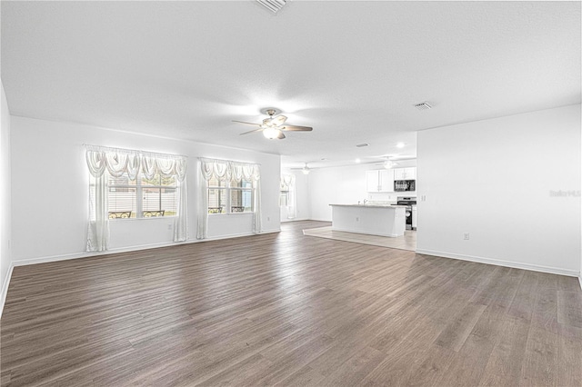 unfurnished living room featuring ceiling fan, hardwood / wood-style floors, and a textured ceiling