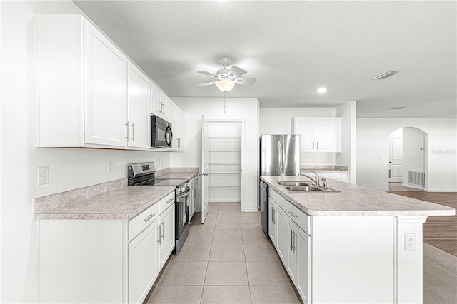 kitchen with a textured ceiling, stainless steel electric range oven, sink, a center island with sink, and white cabinetry