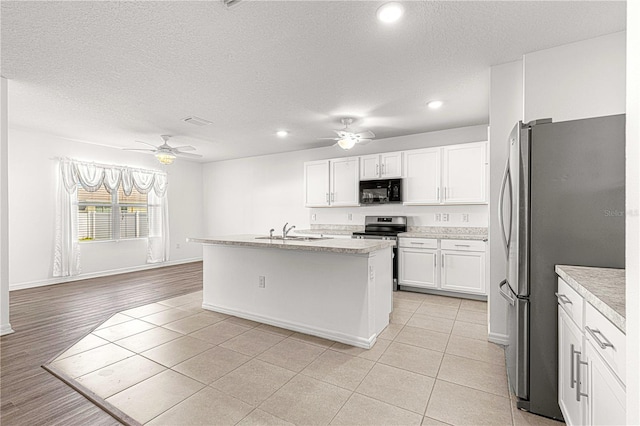 kitchen featuring white cabinetry, sink, stainless steel appliances, light hardwood / wood-style flooring, and a center island with sink