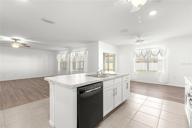 kitchen featuring a healthy amount of sunlight, light wood-type flooring, black dishwasher, and an island with sink