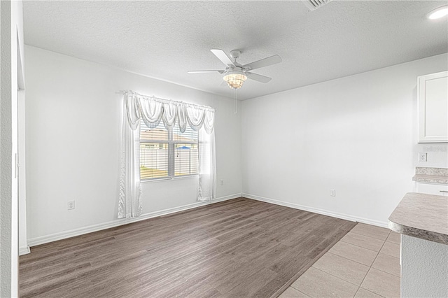 spare room featuring ceiling fan, light hardwood / wood-style floors, and a textured ceiling