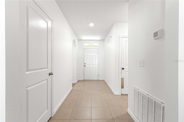 hall with light tile patterned floors and a textured ceiling