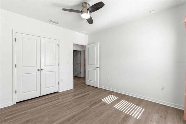 unfurnished bedroom with hardwood / wood-style floors, ceiling fan, and a closet