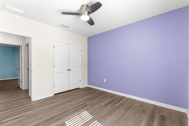 unfurnished bedroom featuring hardwood / wood-style floors, a closet, and ceiling fan