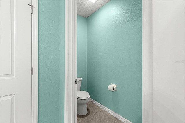 bathroom with tile patterned flooring, a textured ceiling, and toilet