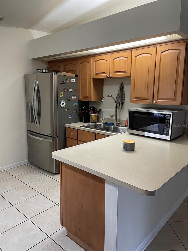 kitchen with kitchen peninsula, light tile patterned floors, sink, and appliances with stainless steel finishes