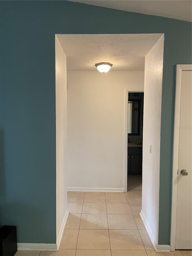 hall with lofted ceiling and light tile patterned floors