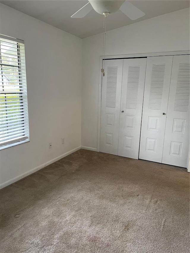 unfurnished bedroom with ceiling fan, a closet, and carpet