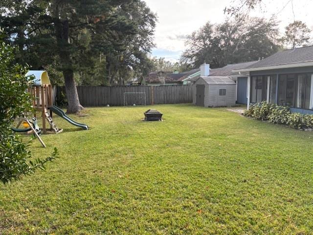 view of yard featuring a playground, a shed, and a fire pit