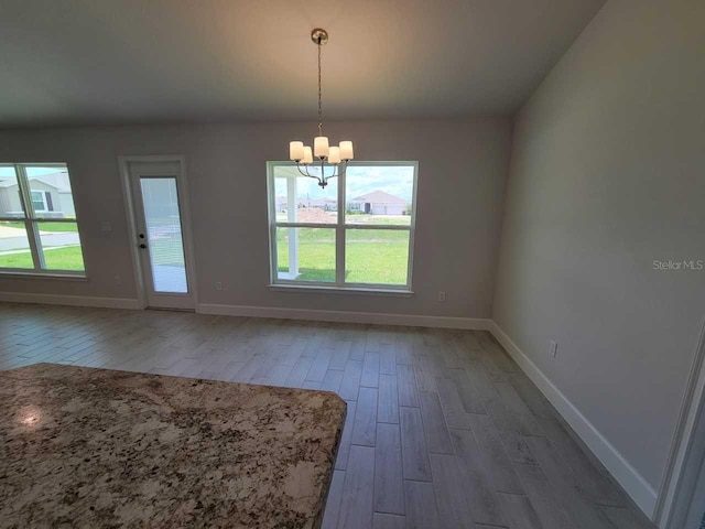 unfurnished dining area with a chandelier and wood-type flooring