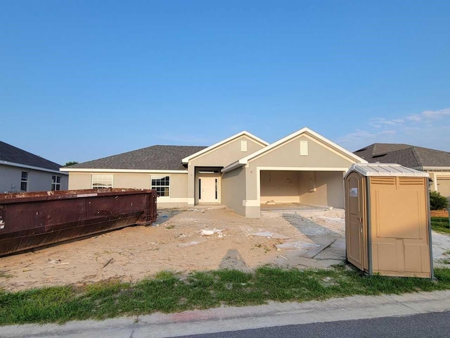 rear view of house featuring fence, stucco siding, and a garage