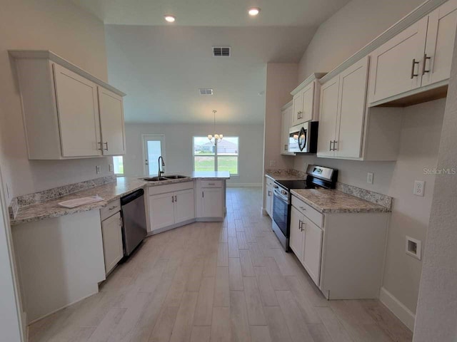 kitchen with a sink, a peninsula, visible vents, baseboards, and appliances with stainless steel finishes