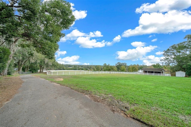 view of yard featuring an outbuilding, a rural view, and fence