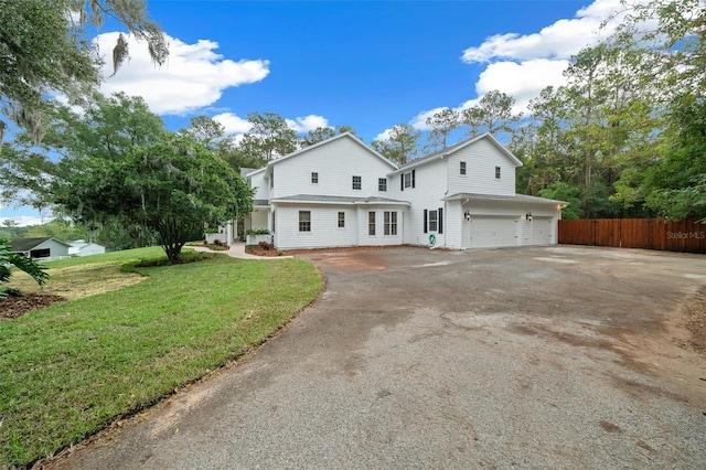 view of front of house with a front lawn, an attached garage, fence, and driveway