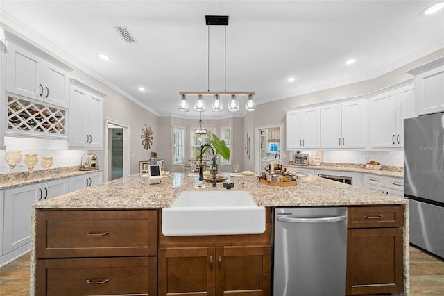 kitchen featuring visible vents, ornamental molding, a sink, appliances with stainless steel finishes, and tasteful backsplash