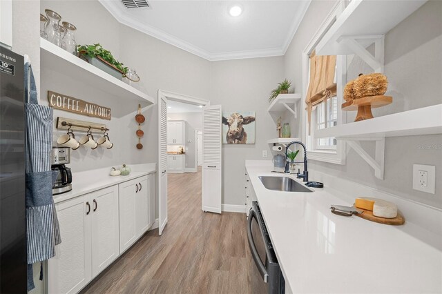 kitchen featuring open shelves, dishwasher, crown molding, and a sink