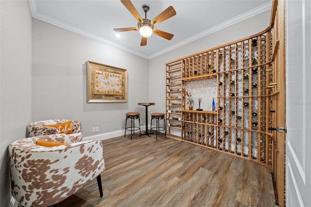 wine area with crown molding, baseboards, and wood finished floors