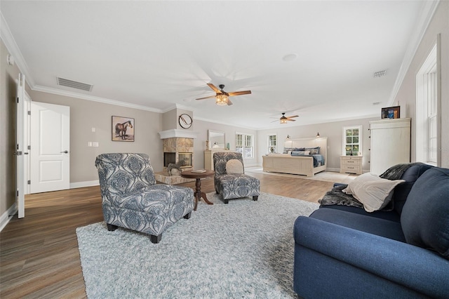 living room featuring visible vents, wood finished floors, crown molding, and a premium fireplace