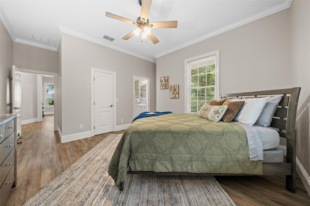 bedroom with crown molding, wood finished floors, visible vents, and baseboards